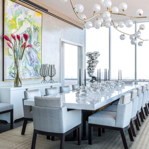 A beautifully designed dining room in a transitional design style and small pops of color in the art.