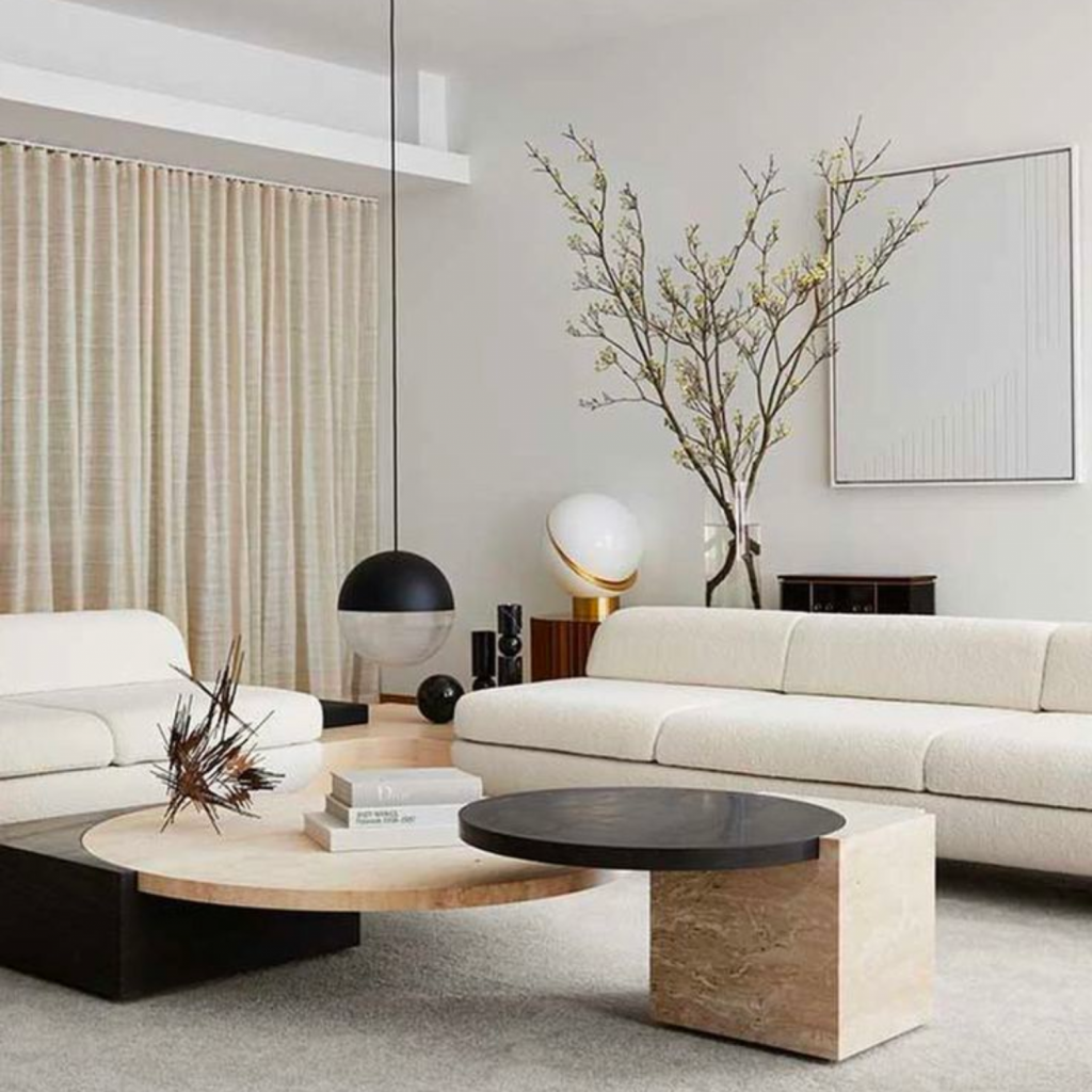 Minimalist interior design style living room presented with a neutral color palette with mainly whites and blacks.    Sofa has clean lines and is uncomplicated.  Minimal decor is incorporated and small detailing.